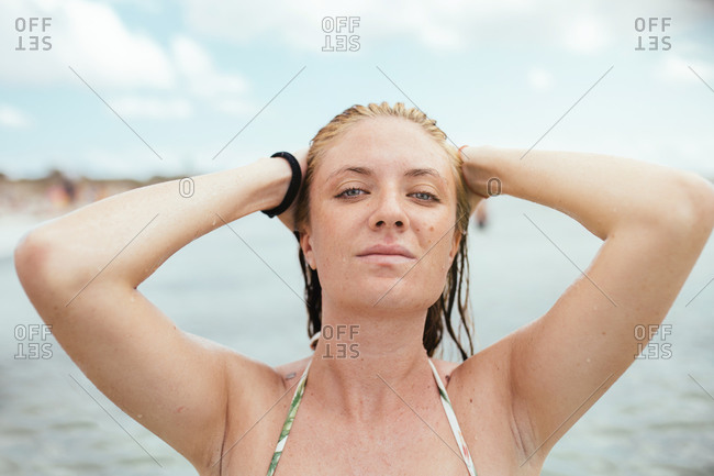 Young blonde woman touching her wet hair in the mediterranean sea