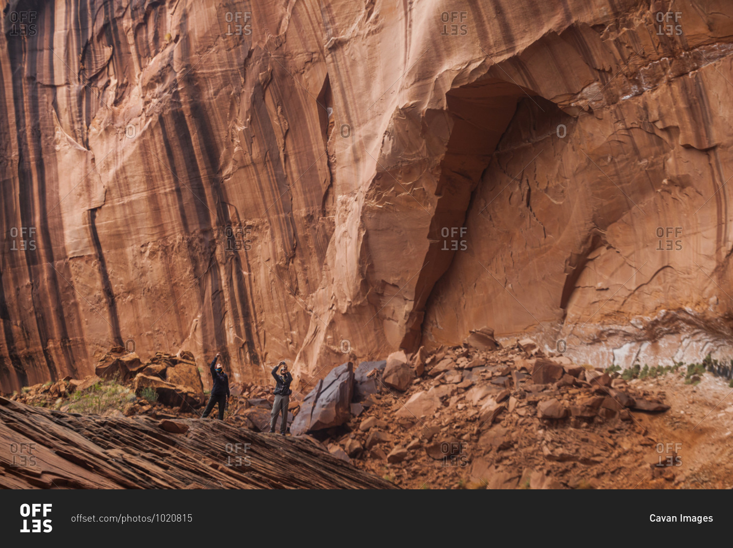People below high sandstone canyon walls near escalante river, utah