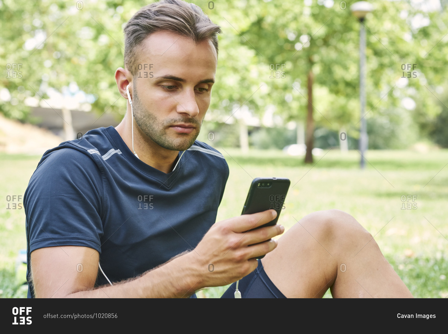 Man with his smart phone sitting on the grass in a park after training. healthy and healthy life. health and sport concept.