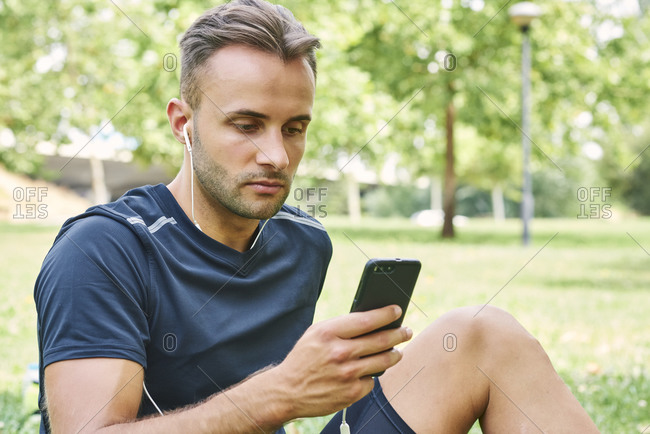 Man with his smart phone sitting on the grass in a park after training. healthy and healthy life. health and sport concept.