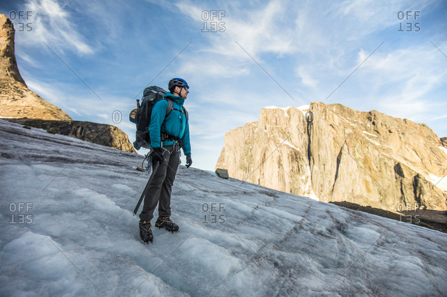 Backpacker standing on glacier below mountain summit.