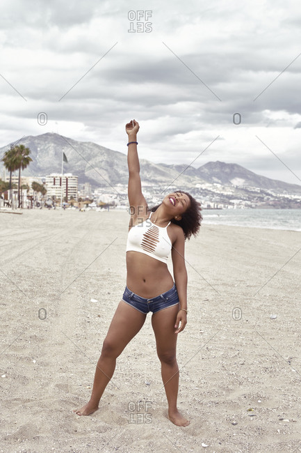 Black woman in short jeans poses spleens high on the beach