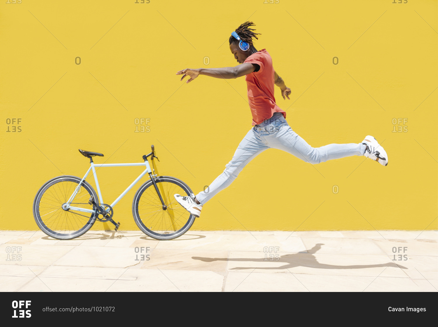 Black male leaping near bicycle