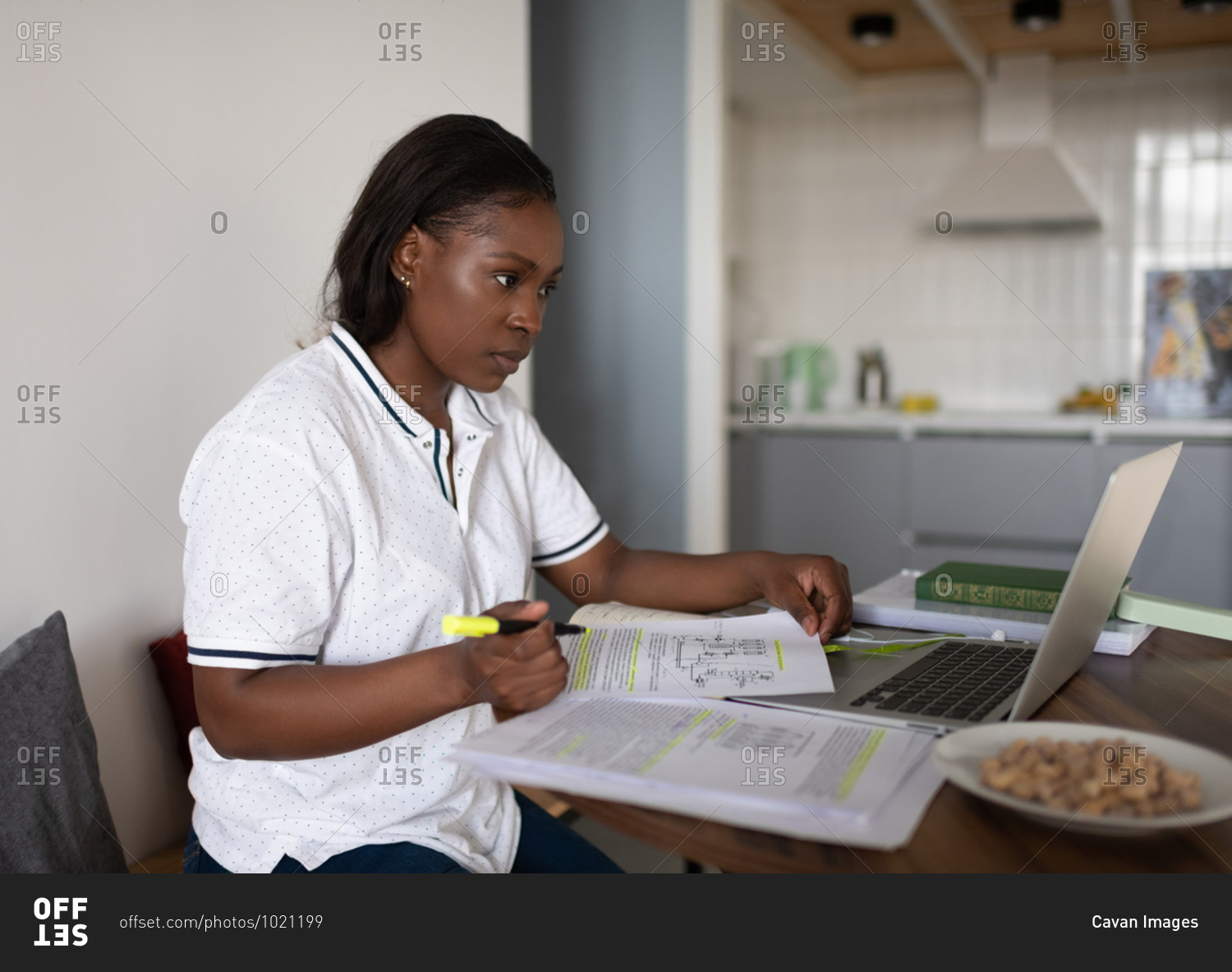 Black student with papers using laptop