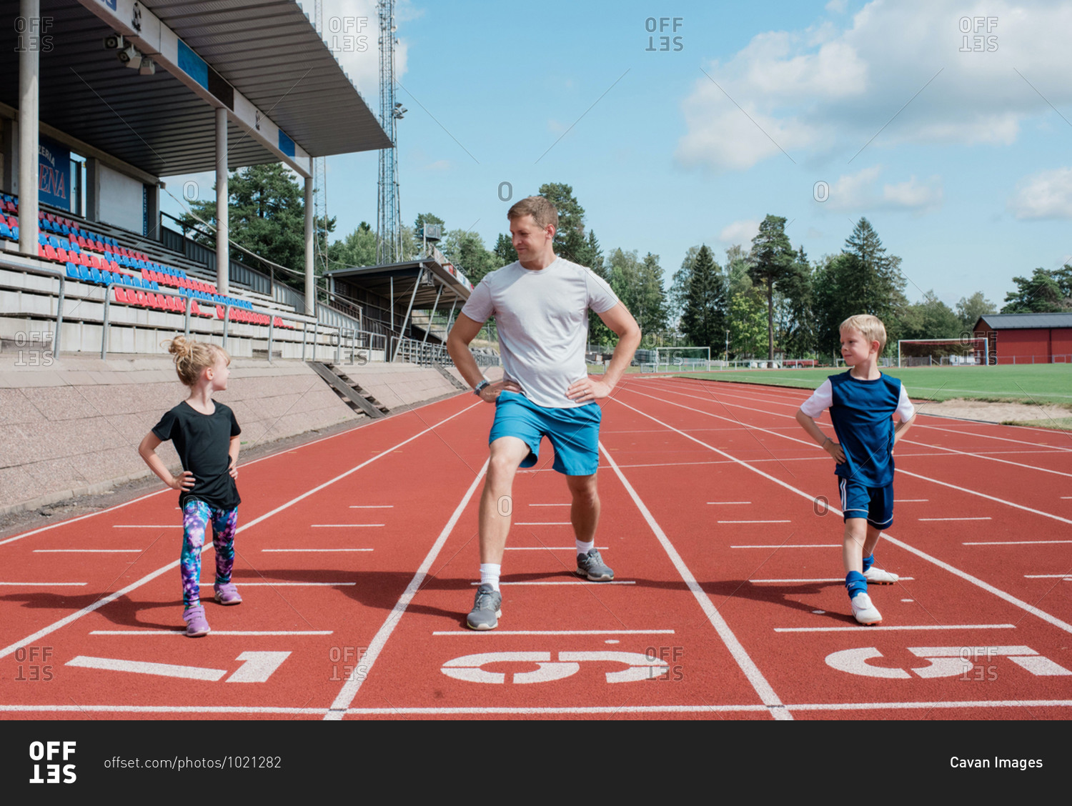 Father doing stretches with his kids on a race track