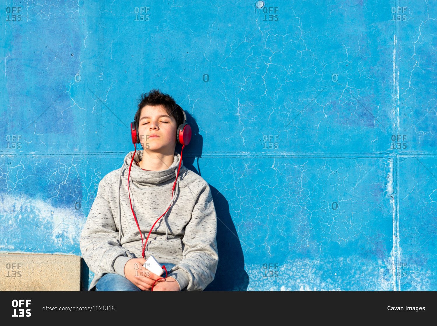Teenager with headphones listening music while sitting on staircase.