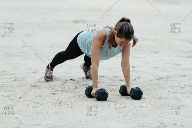 Young woman doing weight training in urban environment.