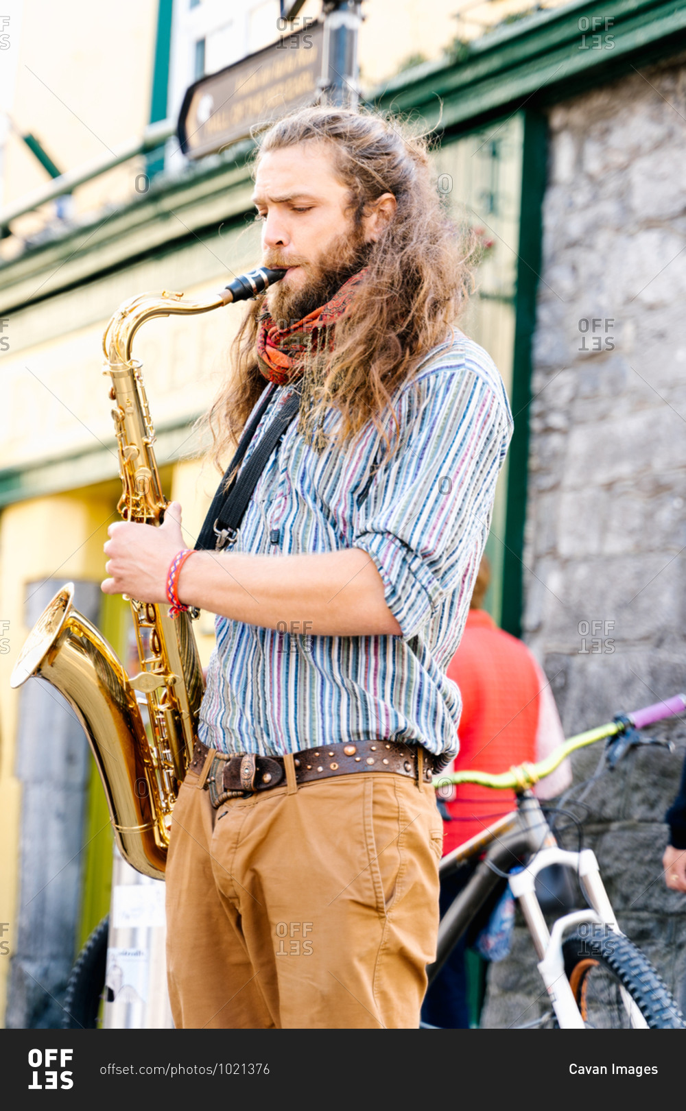 Young man playing saxophone in a crowded street