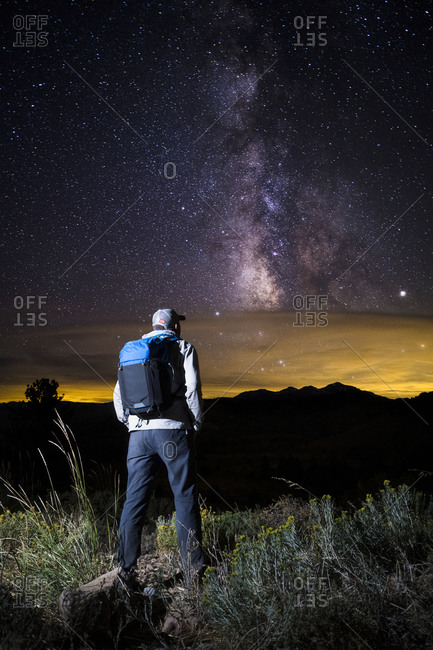 A hiker stands under the milky way and night sky on monitor pass, ca