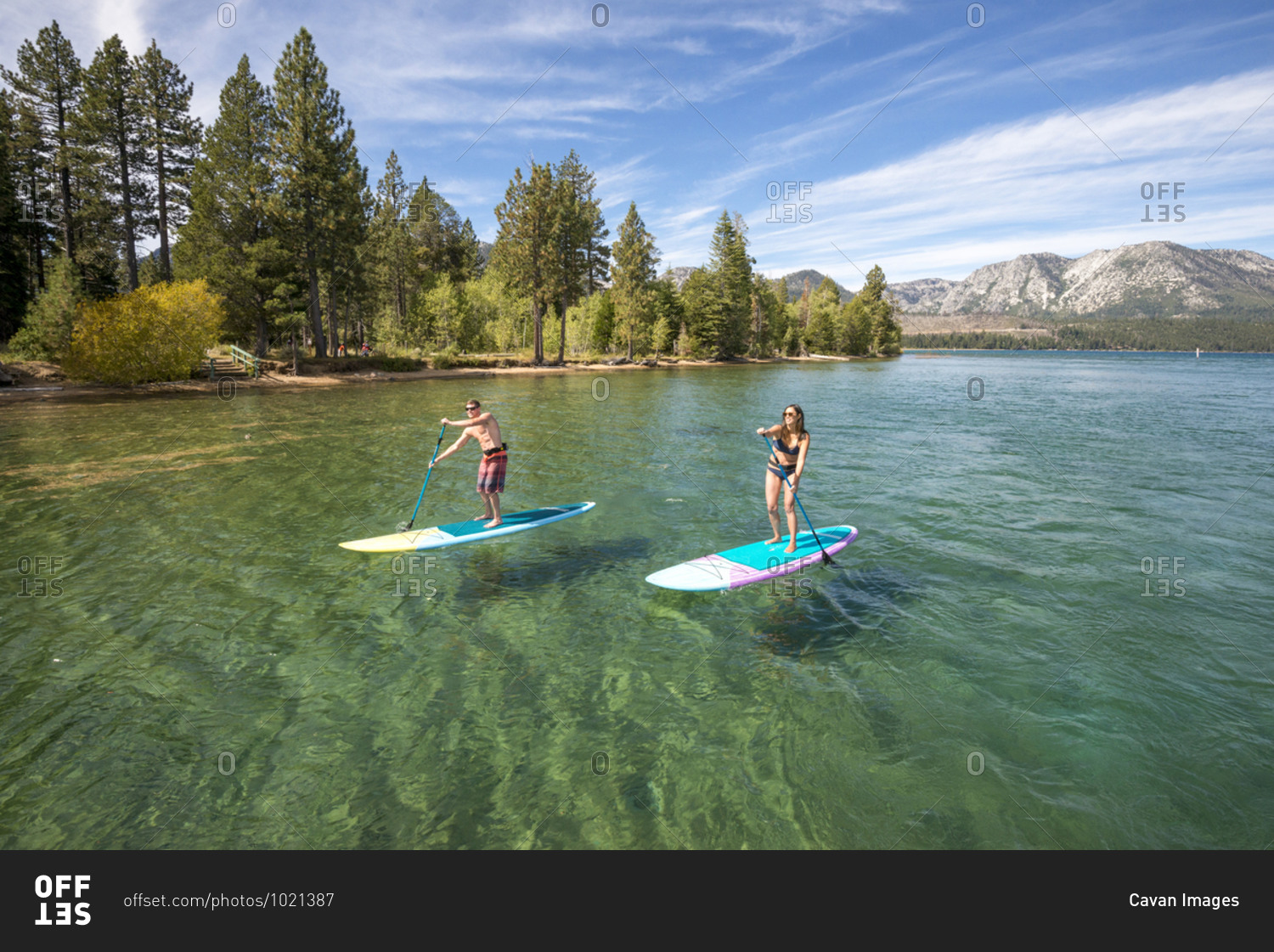 A man and woman stand up paddle boarding on lake tahoe, ca