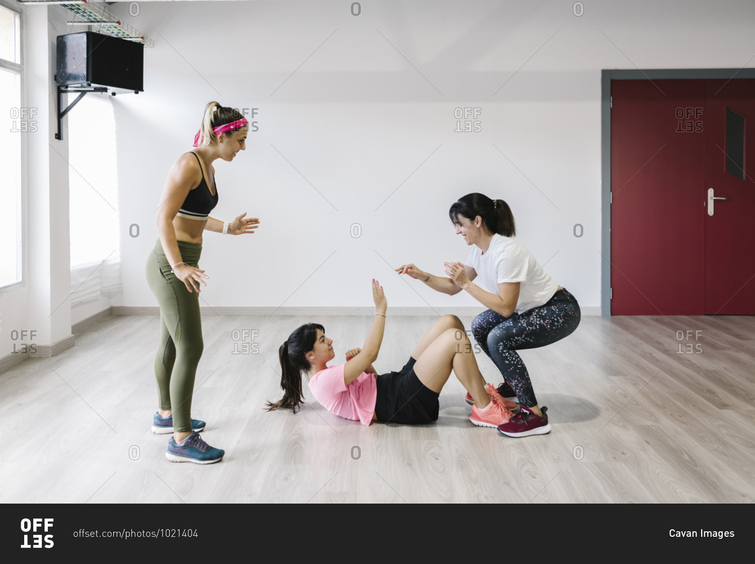 Young and older women in sportswear training with their personal trainer in gym
