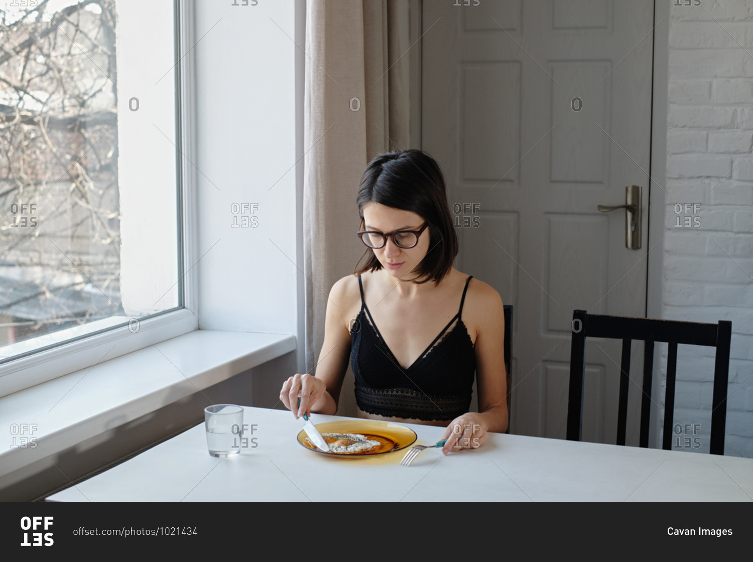 Young woman in lingerie having breakfast by the table