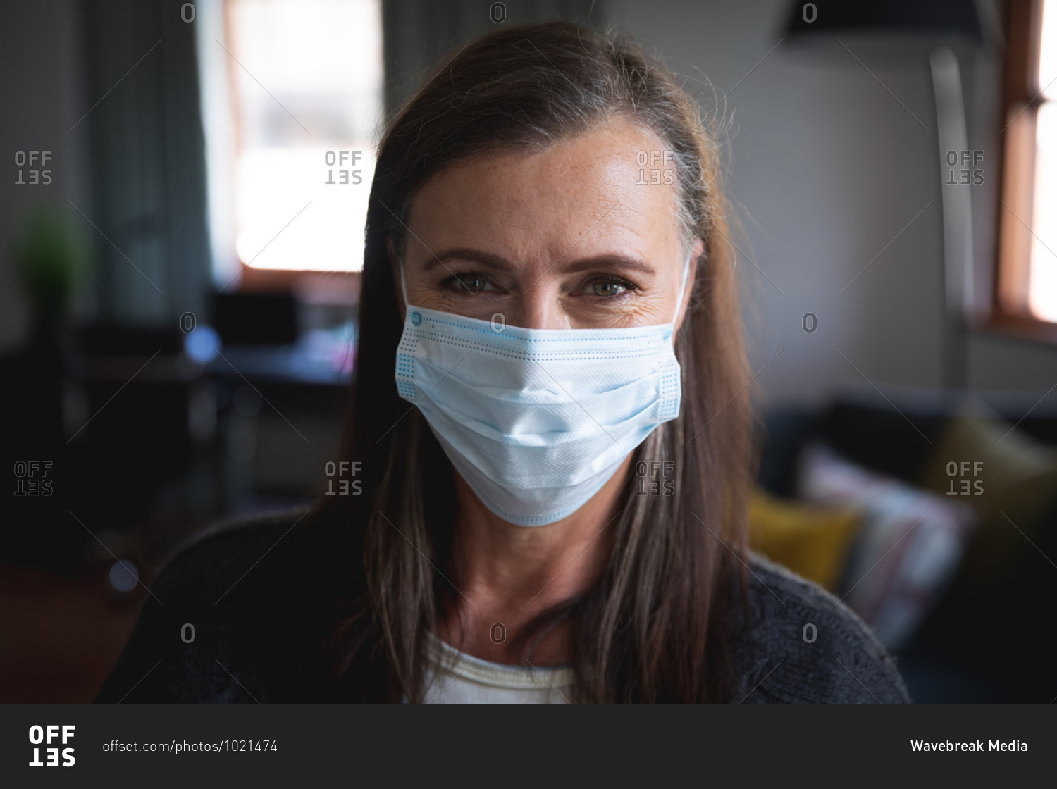 Portrait of Caucasian woman enjoying time at home, social distancing and self isolation in quarantine lockdown, wearing face mask protecting from Covid 19 coronavirus infection, looking at camera.