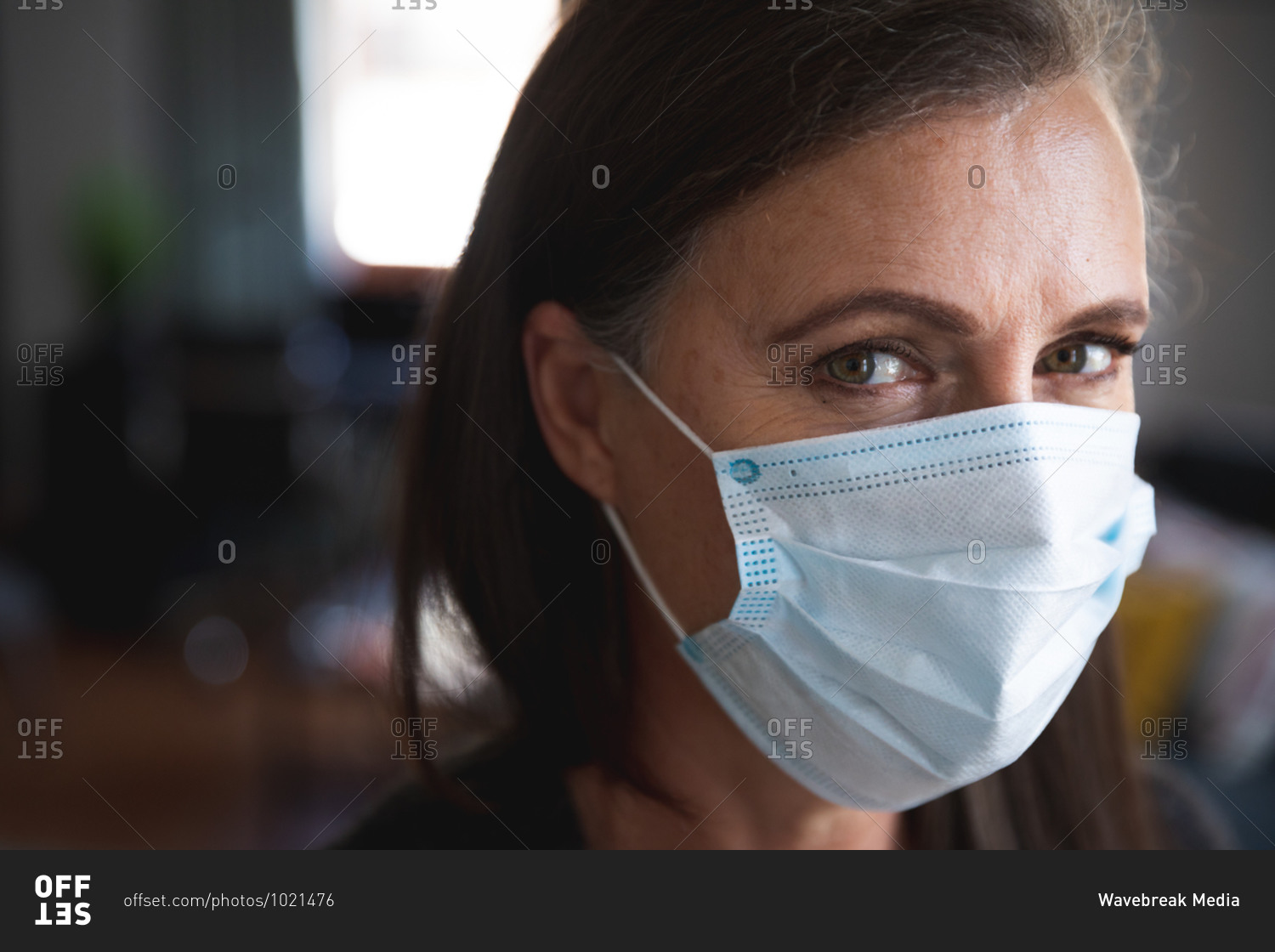 Portrait of Caucasian woman enjoying time at home, social distancing and self isolation in quarantine lockdown, wearing face mask protecting from Covid 19 coronavirus infection, looking at camera.