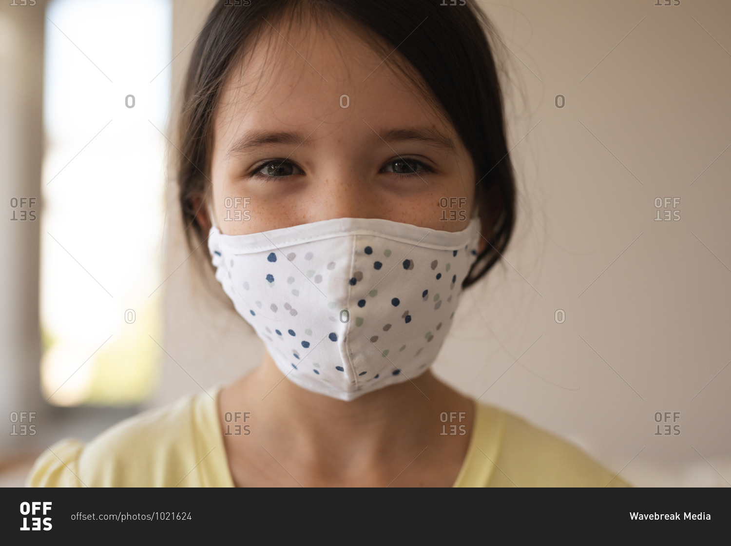 Portrait of Caucasian girl spending time at home, wearing face mask, looking at camera. Social distancing during Covid 19 Coronavirus quarantine lockdown.