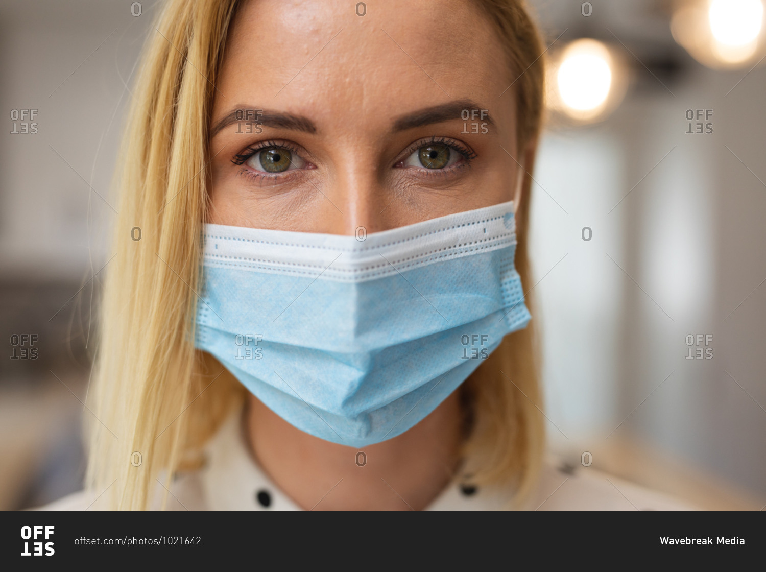 Portrait of Caucasian woman spending time at home, wearing face mask, looking at camera. Social distancing during Covid 19 Coronavirus quarantine lockdown.