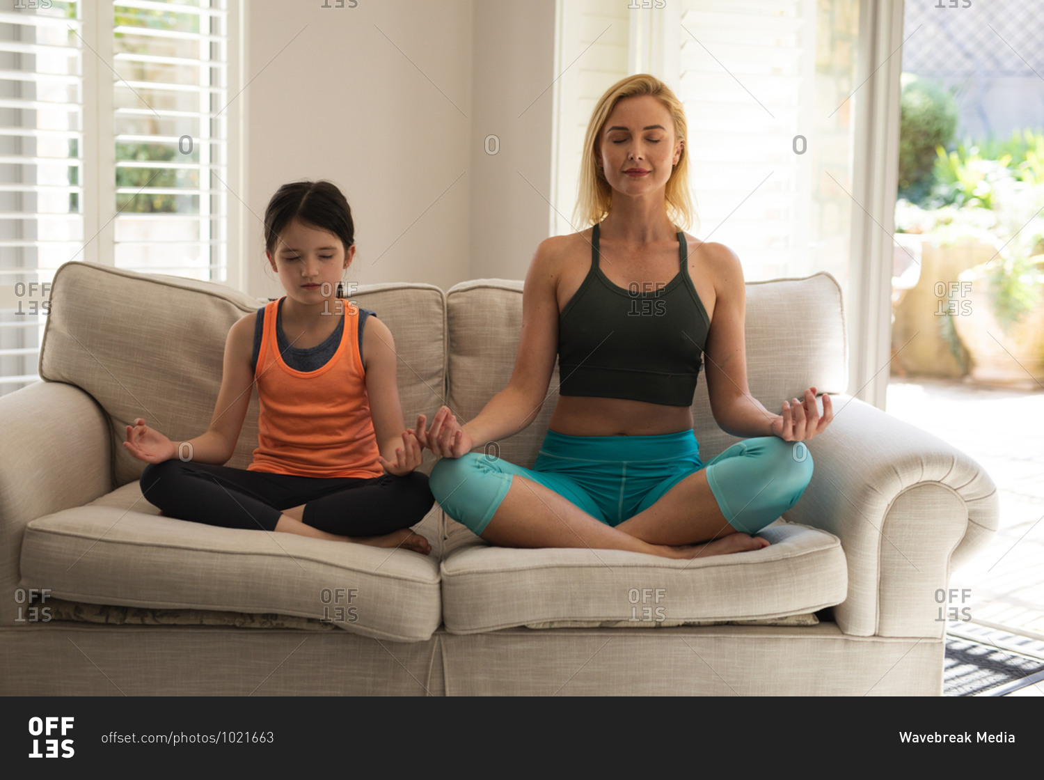 Caucasian woman and her daughter spending time at home together, doing yoga, meditating. Social distancing during Covid 19 Coronavirus quarantine lockdown.