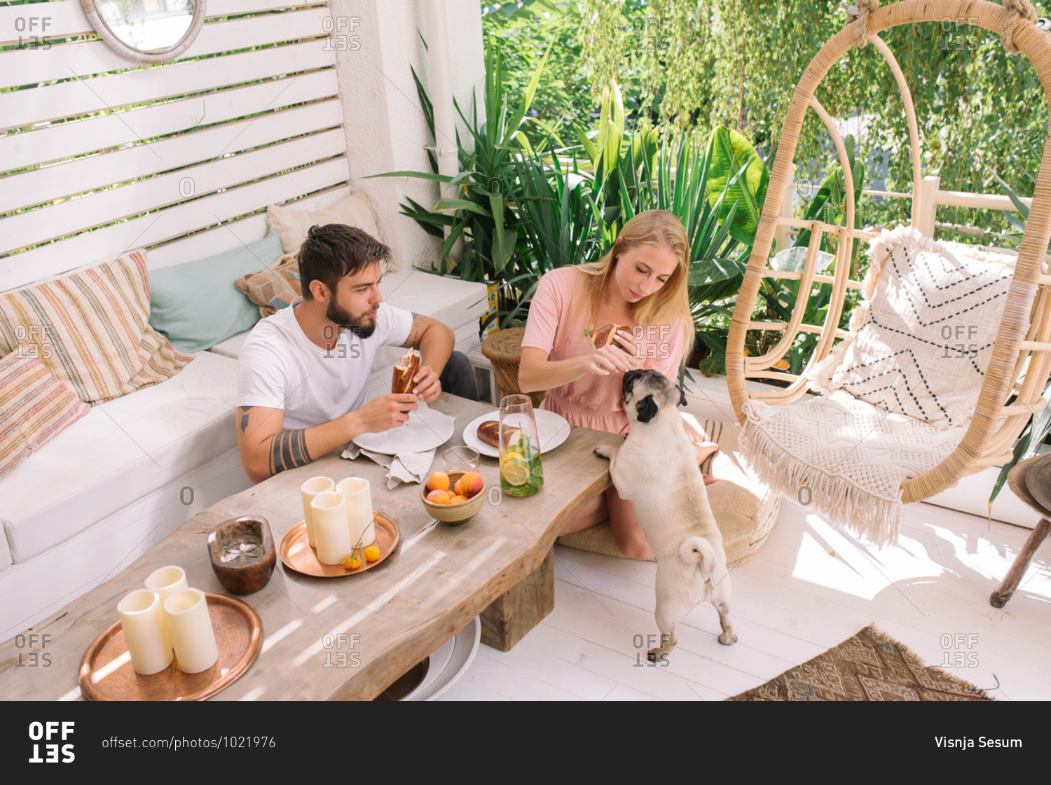 Young couple having breakfast with dog in their beautiful boho style apartment