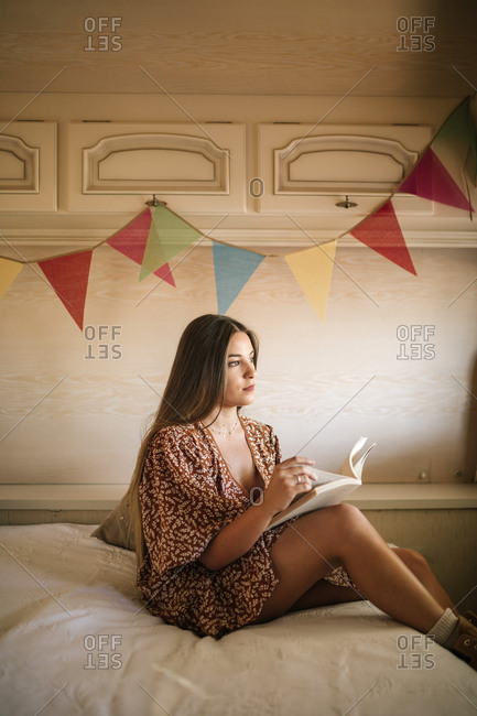Young woman reading a book inside a caravan