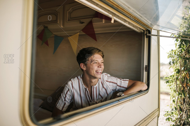 Portrait of young blond man smiling inside a caravan