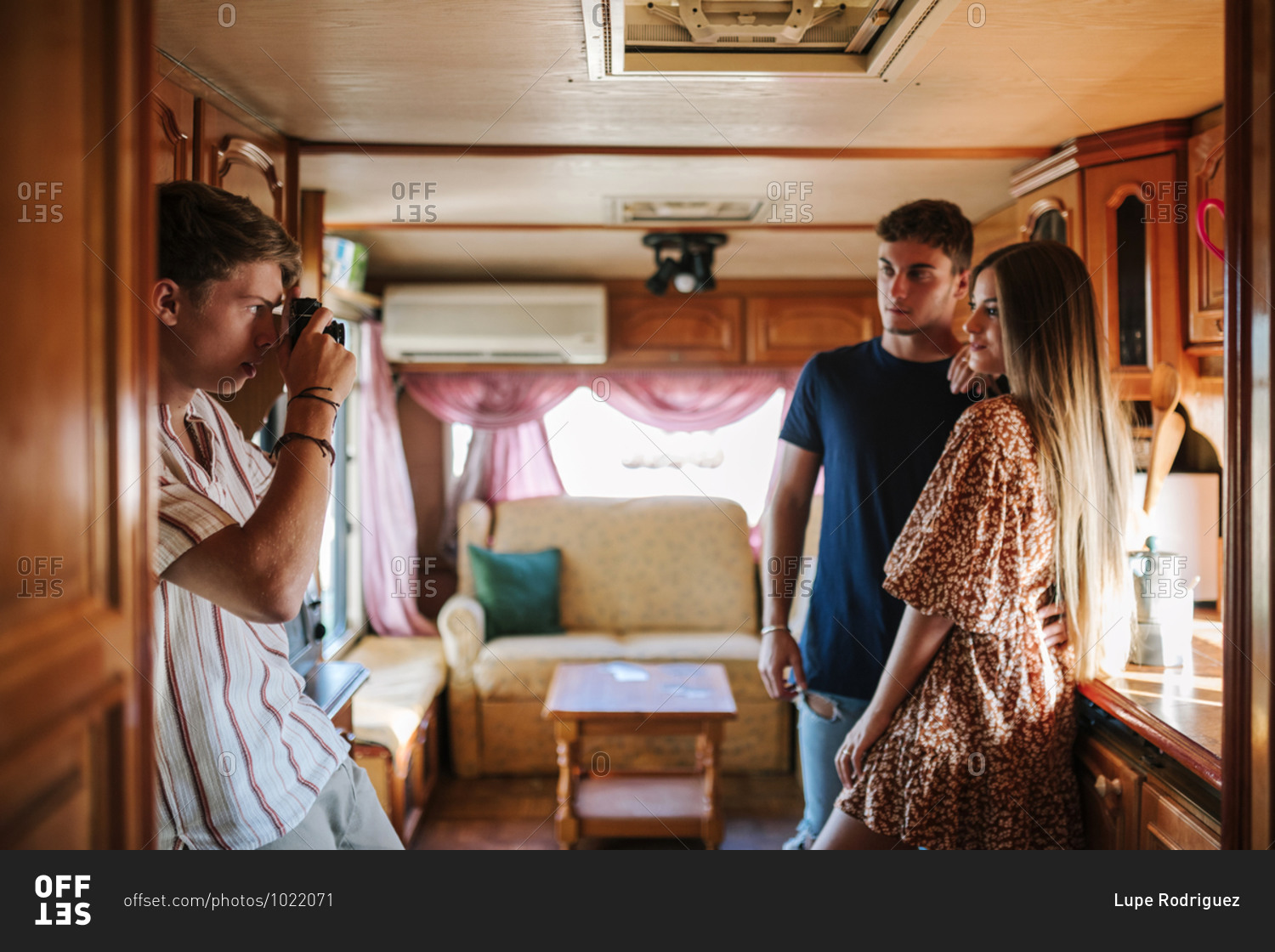 Young man with a camera taking photos of his friends inside a caravan