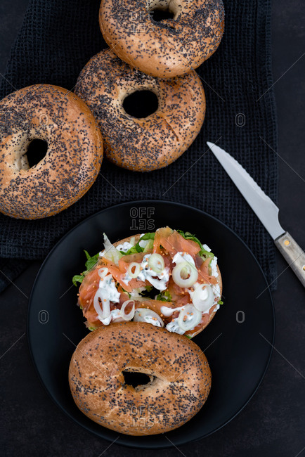 Salmon lox bagel with cream cheese and veggies on a dark setting