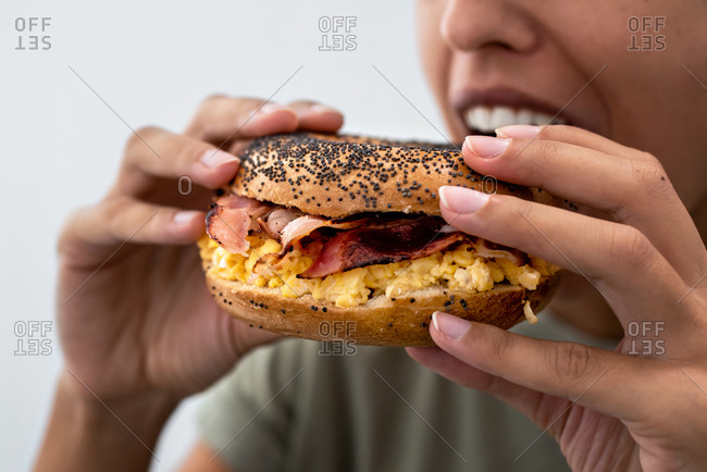 Woman eating a bagel with bacon and egg
