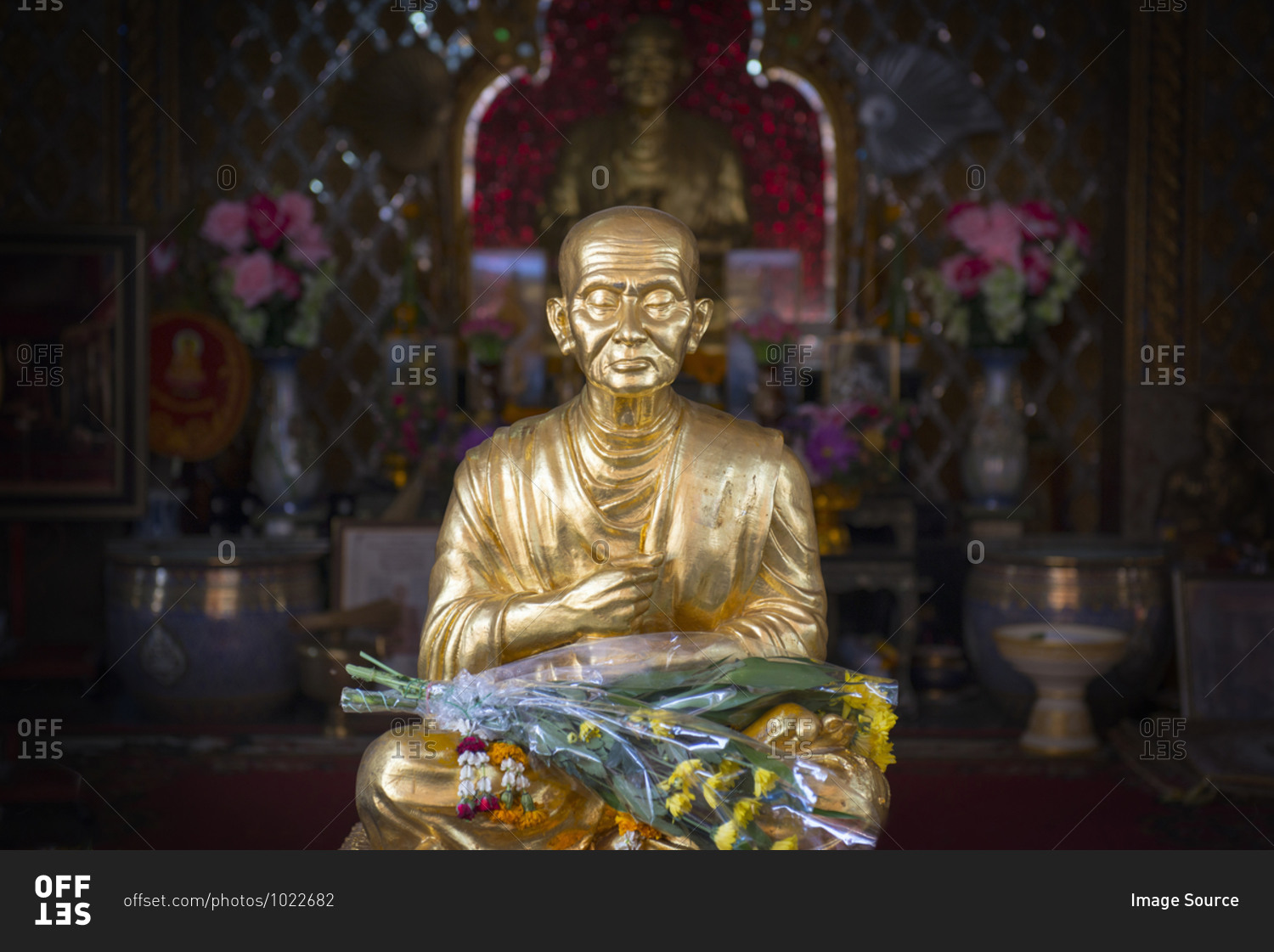 Golden buddha statue adorned with flowers