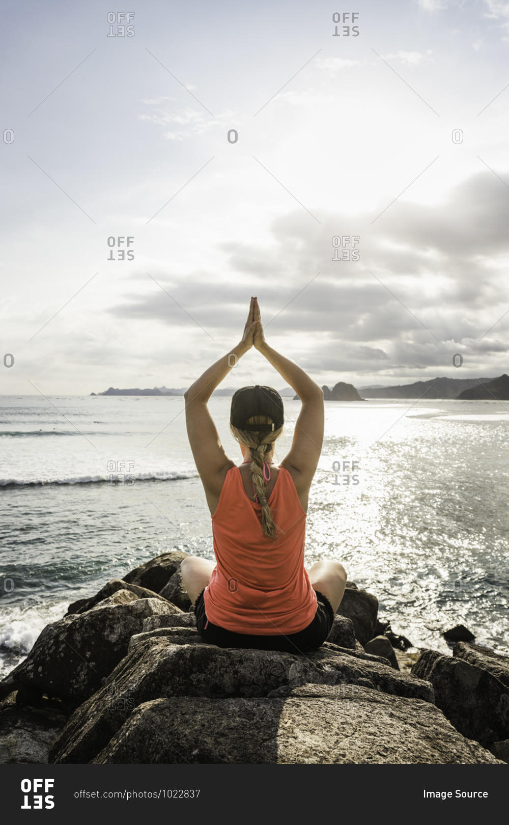 Tourist practicing yoga on rocks, Mawi Beach, Lombok, Indonesia