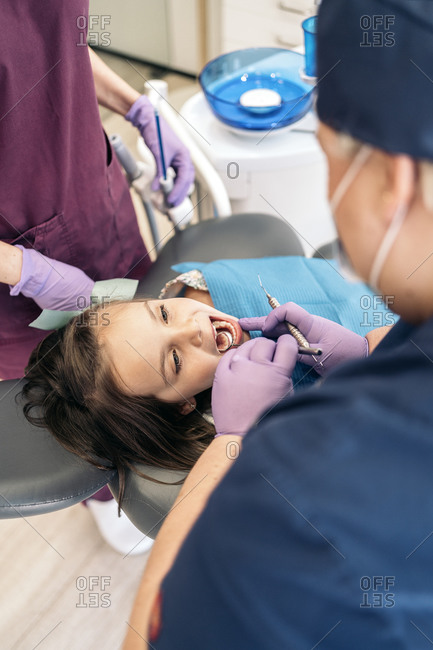 Dentists performing an exam on a young girl in a dentist office