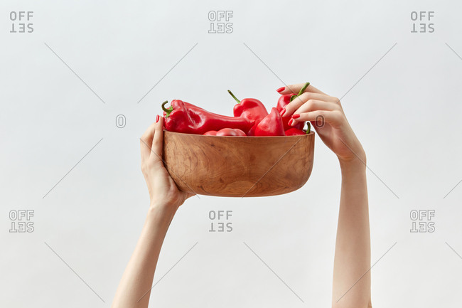 Wooden plate with organic paprika in woman's hands.