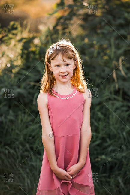 Portrait of a young girl wearing a pink dress outside at sunset