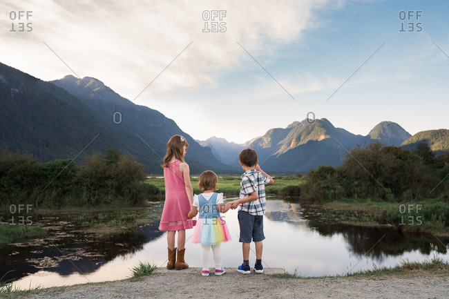 Three siblings standing and looking out at Pitt Lake in British Columbia, Canada