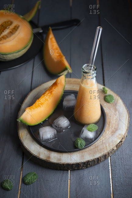 Cantaloupe melon fresh juice in a little glass bottle with ice cubes and mint
