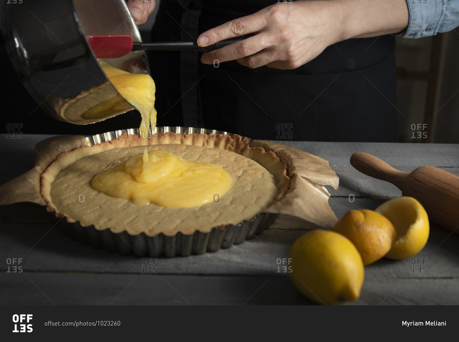 Hands pouring a lemon curd on a baked short crust pastry crust