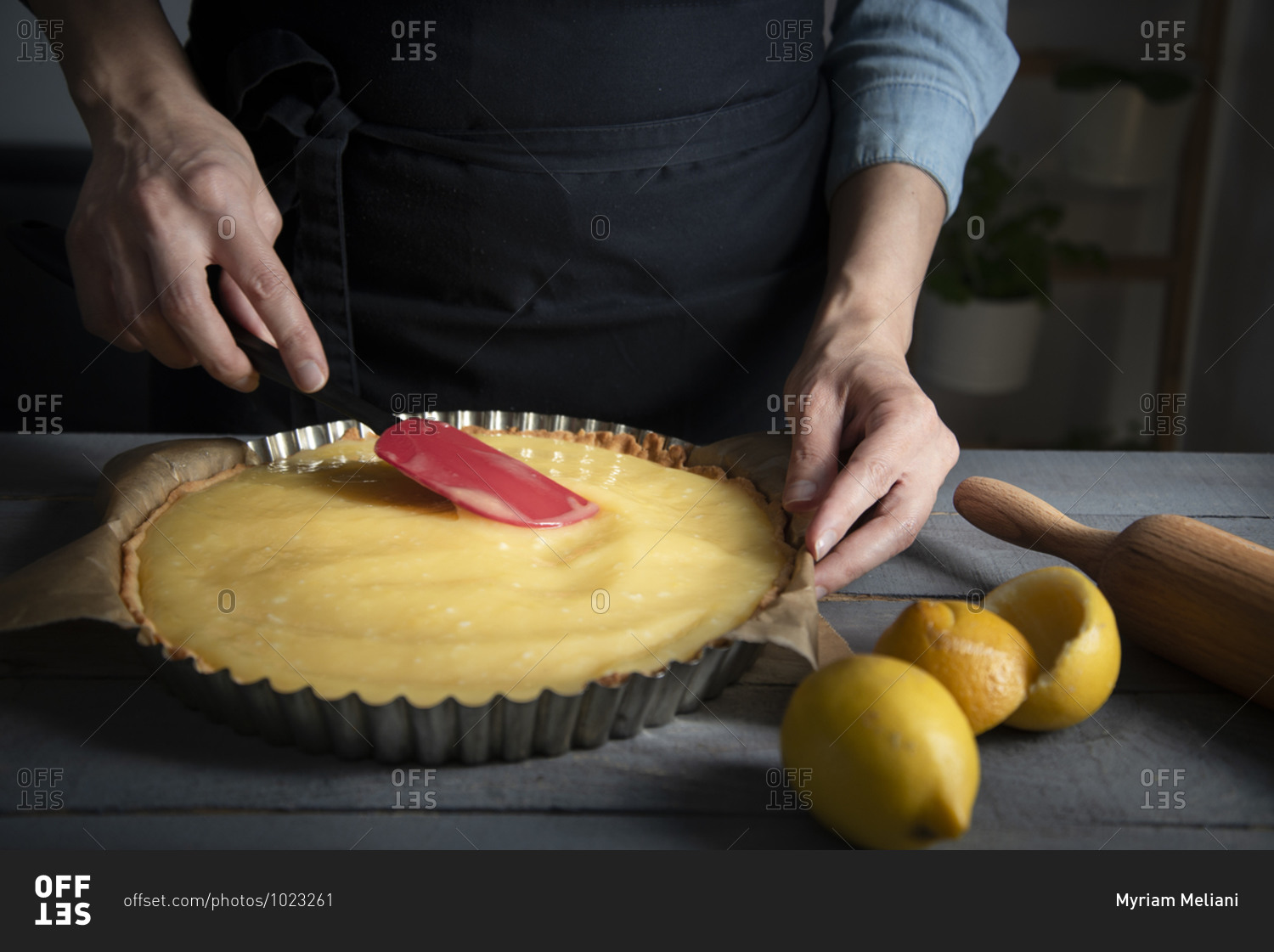 Hands smoothing out a lemon curd on a baked short crust pastry crust