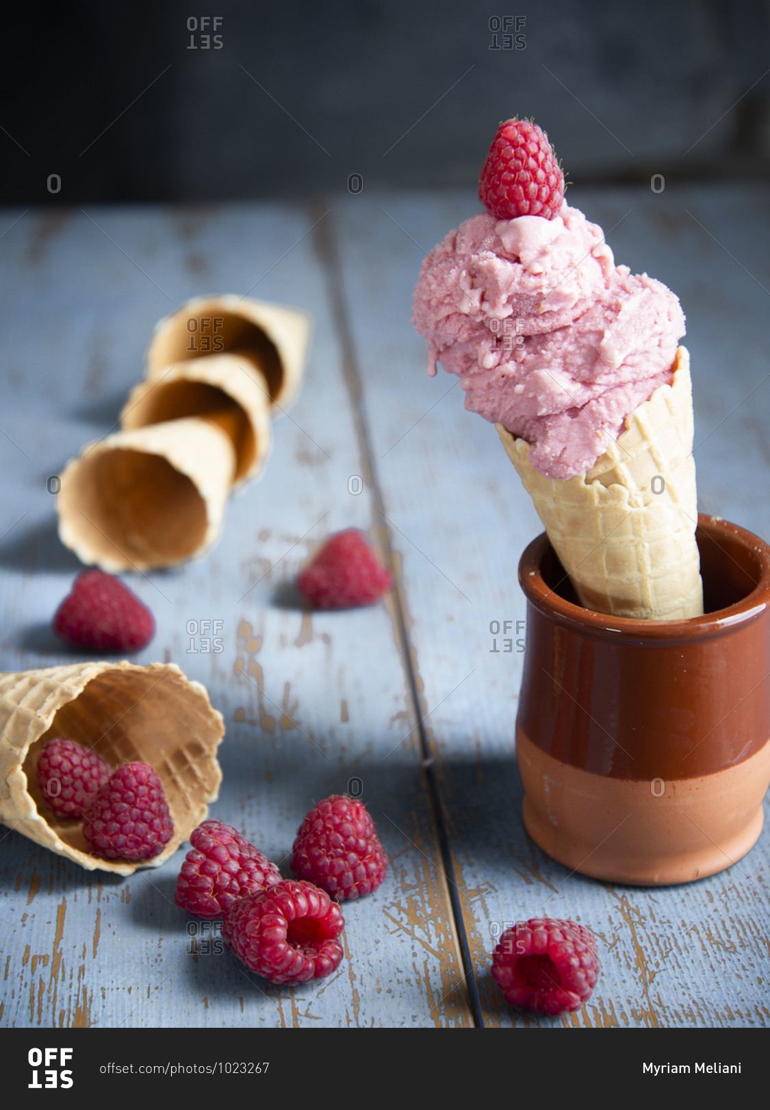 Raspberry ice cream in a waffle cone with fresh raspberries