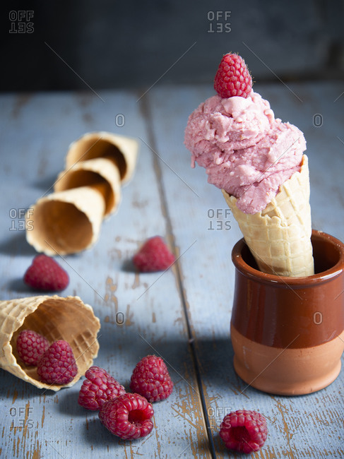 Raspberry ice cream in a waffle cone with fresh raspberries