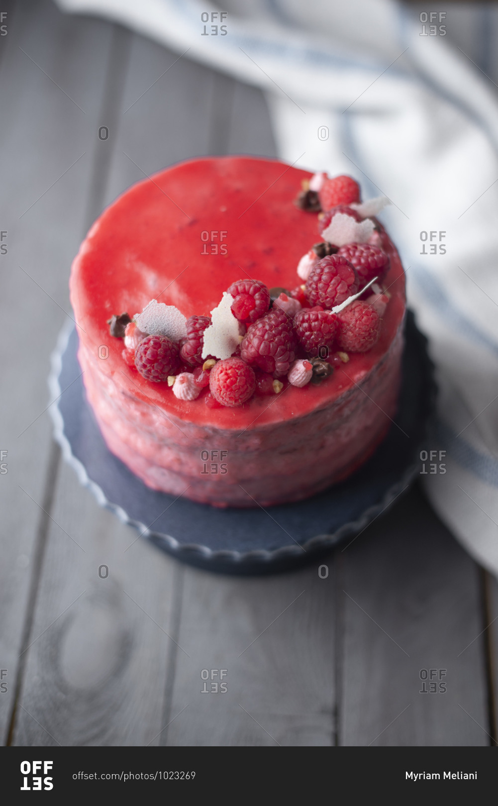 Red glazed raspberry layer cake on a wooden table