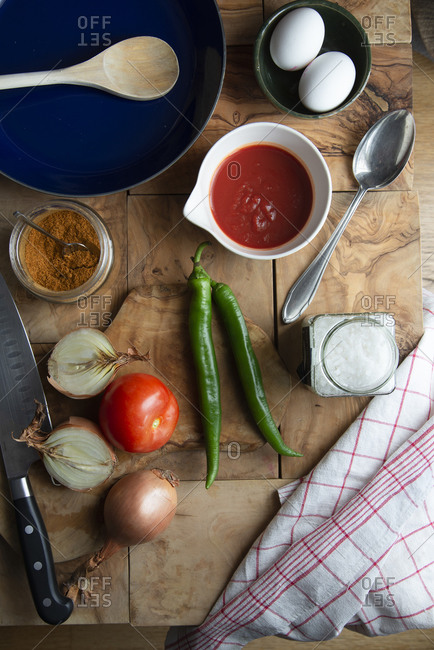 Layout with the ingredients of a Tunisian shakshuka on a wooden backdrop