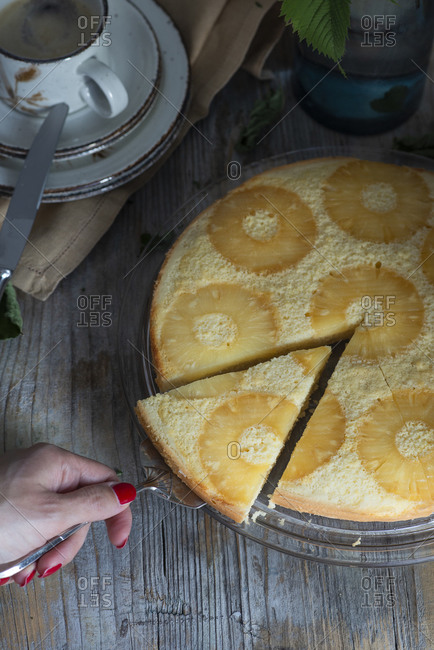 Hand slicing an upside down baked pineapple cake