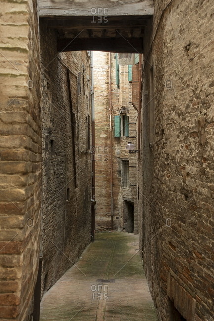 Narrow alleyway surrounded by stone walls in a town in Marche, Italy