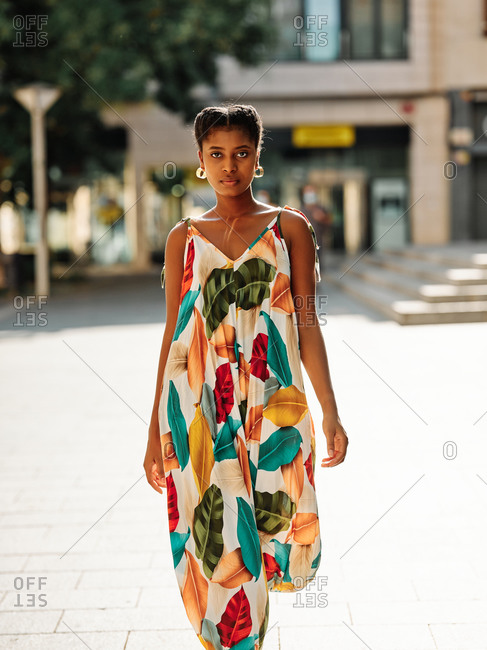 Delighted young African American female in stylish colorful outfit spending sunny summer day in park