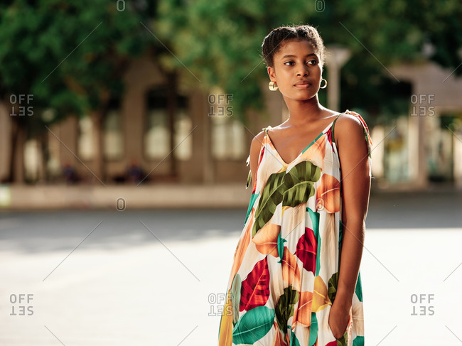 Delighted young African American female in stylish colorful outfit spending sunny summer day in park