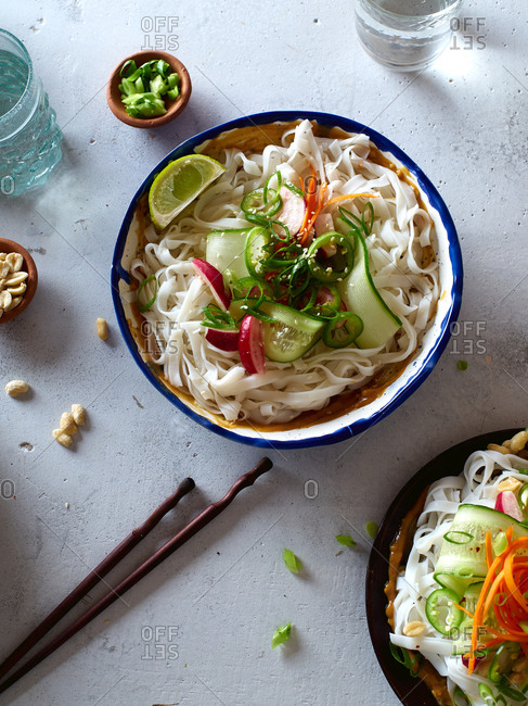 Top view of vegan rice noodle salad made with fresh vegetables, lime and peanut sauce