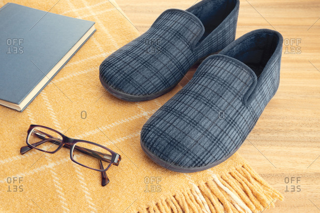 Male home slippers, book, eyeglasses and wool blanket. Home relaxing in wintertime concept