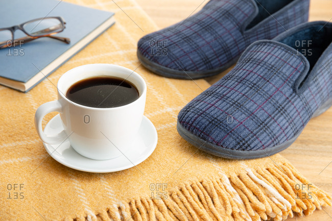 Male home slippers, coffee, book and wool blanket. Home relaxing in wintertime concept