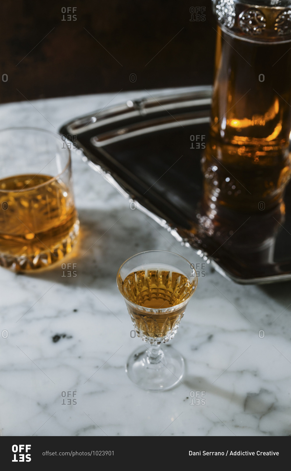 High angle of whiskey in glass and bottle arranged on marble table in bar