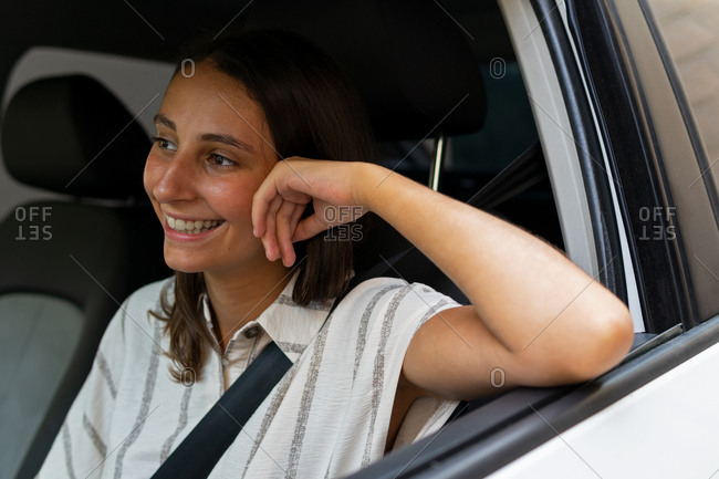 Young smiling female driving modern automobile in city during daytime and looking forward