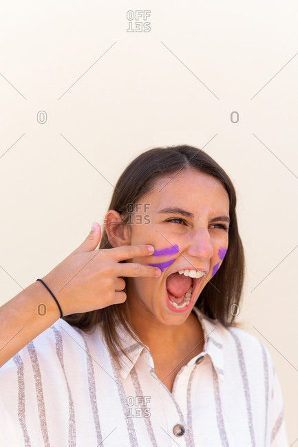 Expressive female with war paint on face screaming in city demonstrating concept of girl power